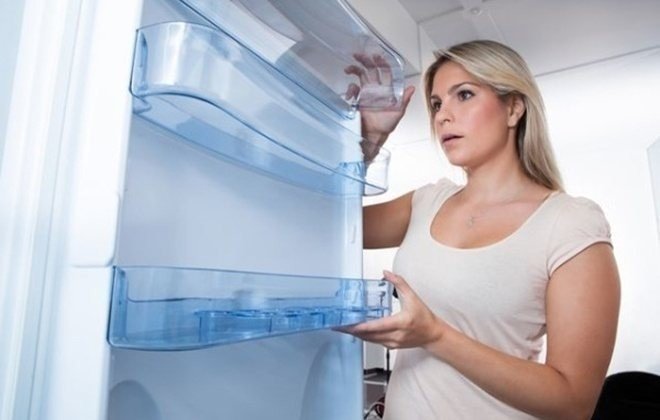 Девушка достает продукты из холодильника